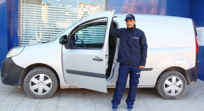 un chauffagiste gasolec pose à coté de son véhicule 