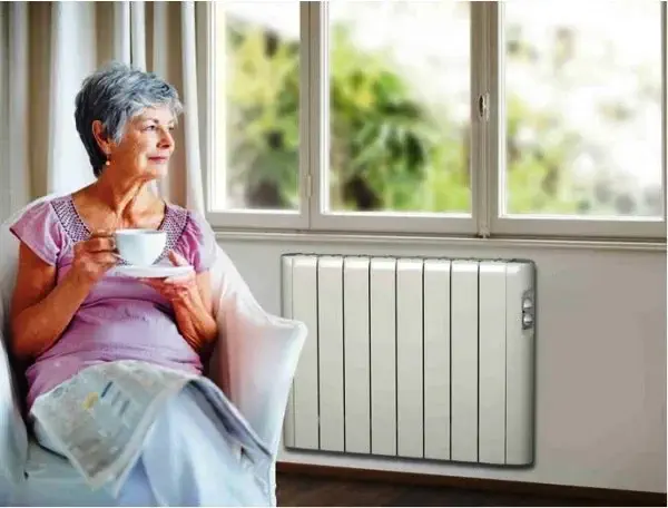 une dame agée installée près d'un radiateur 